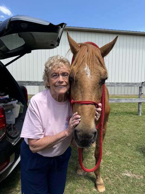 Elderly woman smiling with a chestnut horse