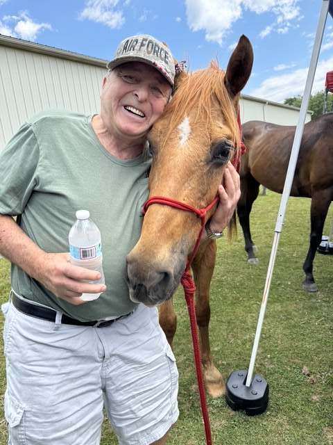Air Force veteran laughing with a chestnut horse