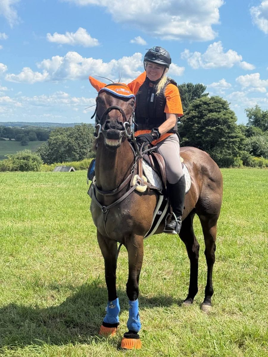 Squishy, a dark bay mare, showing off a big silly grin while out on a ride